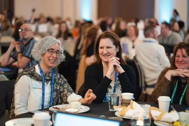 Attendees laughing together at a lunch table